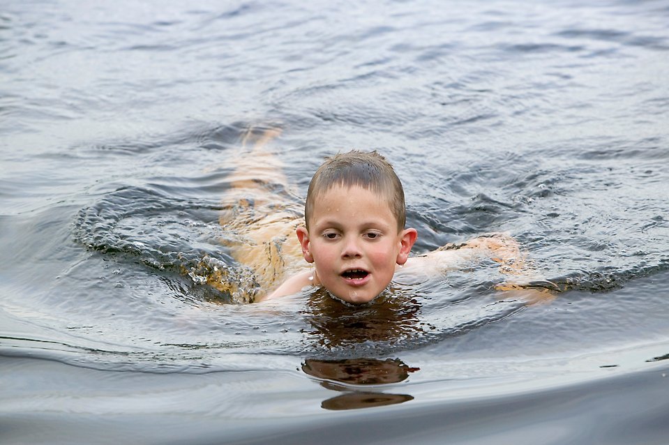 Pojke simmar i en sjö