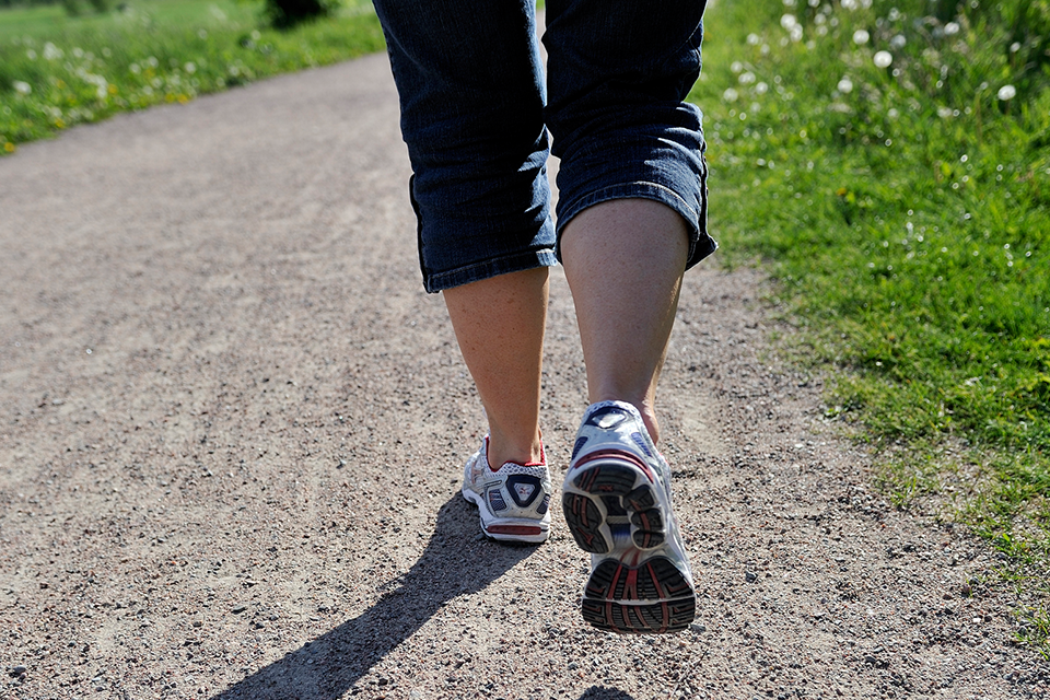 Närbild på fötter som går i joggingskor på en grusväg.