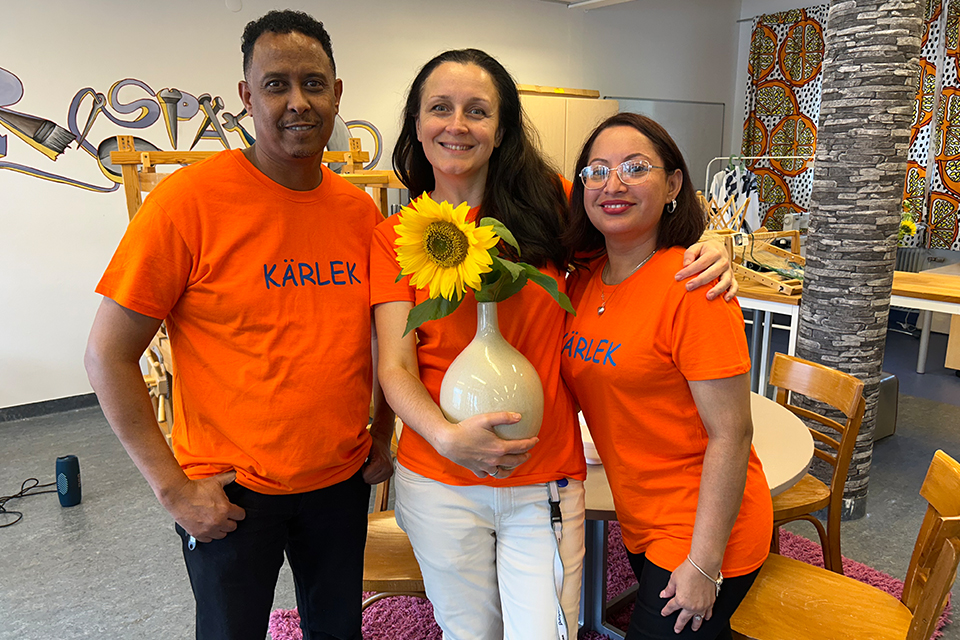 En man och två kvinnor iklädda orangea t-shirts med texten kärlek.