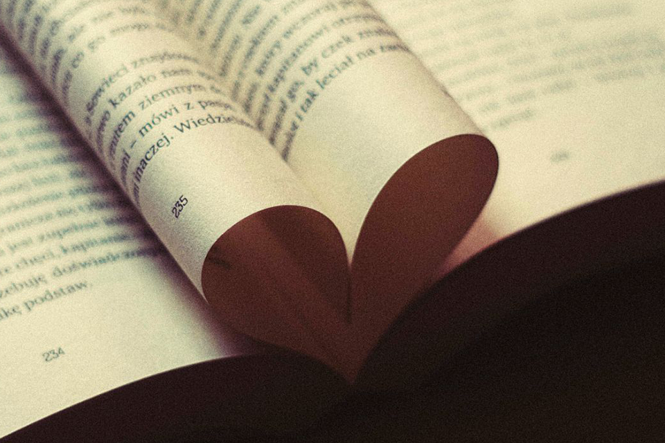 Uppslagen bok med två blad vikta i formen av ett hjärta i mitten.