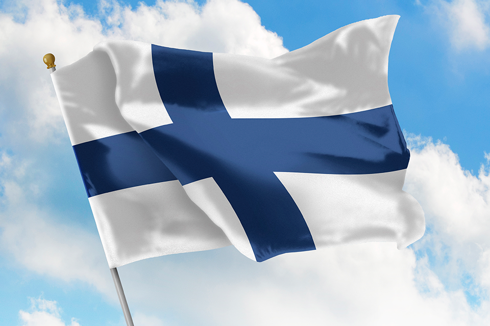 Finlands flagga vajar mot blå himmel med små vita moln