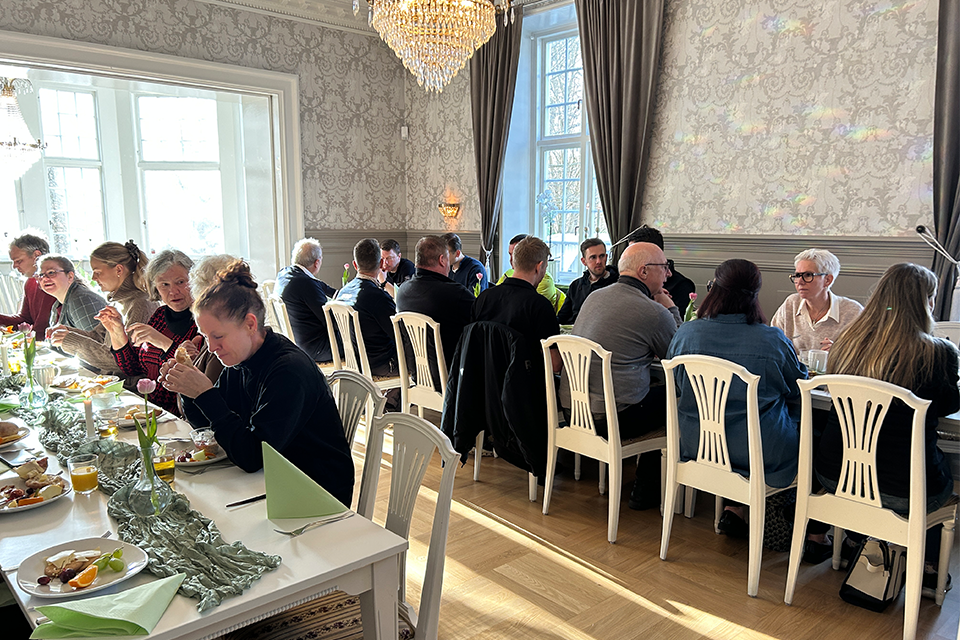 Två långbord där personer sitter med frukosttallrikar.