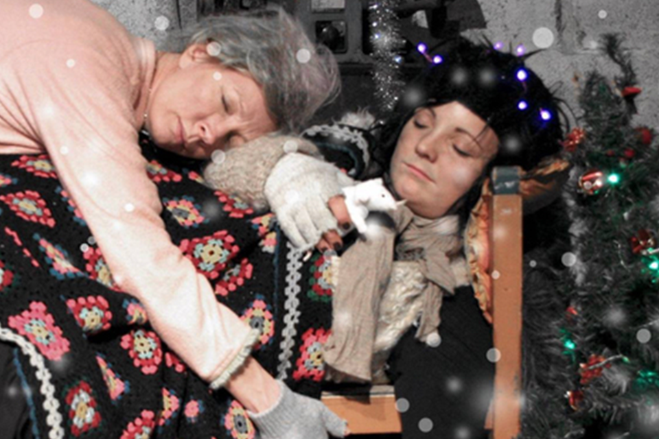 Två kvinnor ligger bredvid en julgran och sover.