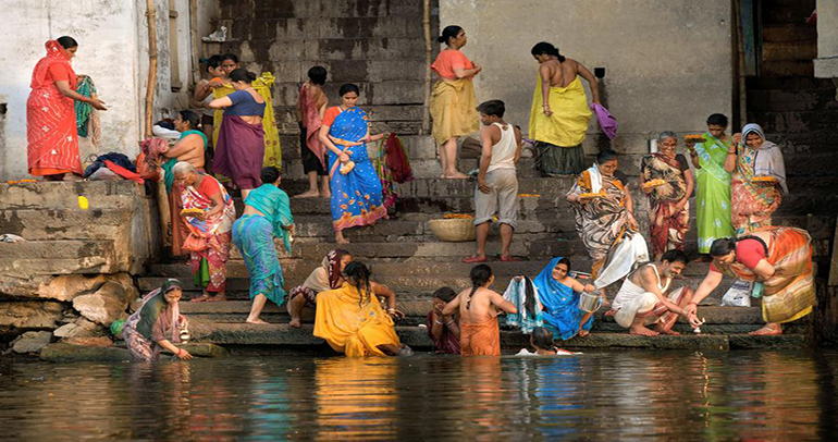Ett flertalet personer på en trappa som leder ner i floden Ganges