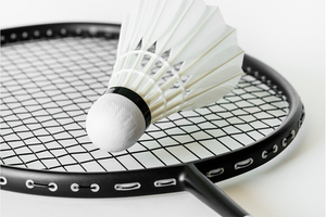 badmintonrack och fjäderboll ligger på ett vitt golv