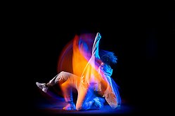 Dansare mot svart bakgrund. Effektfull och färgstark bild där man ser rörelsen.