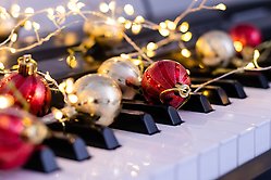 Pianotangenter dekorerade med julkulor och ljusslinga