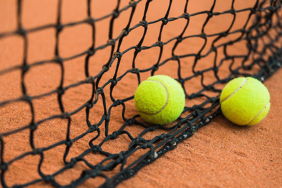 Två tennisbollar ligger i ett nät i en inomhushall