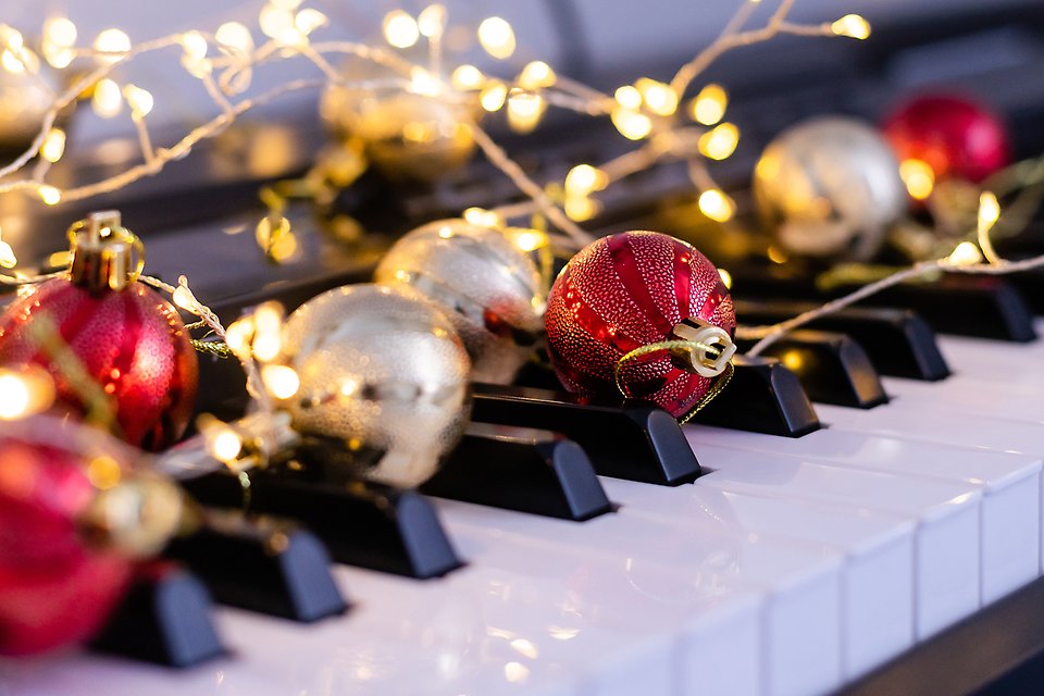Pianotangenter dekorerade med julkulor och ljusslinga